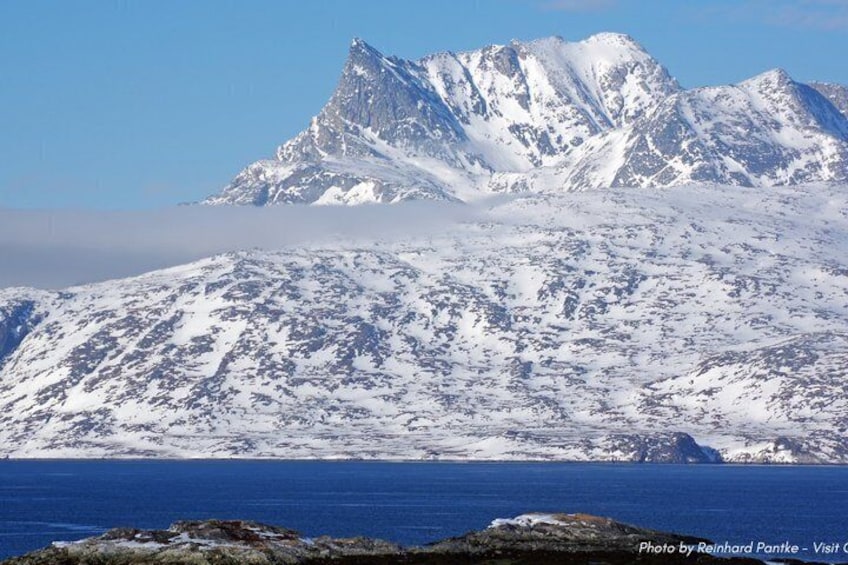 A snow-covered mountain range with a clear blue sky. 5