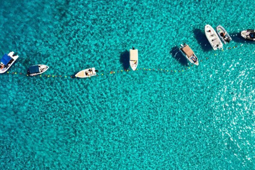 A turquoise sea with boats anchored in a line. 3