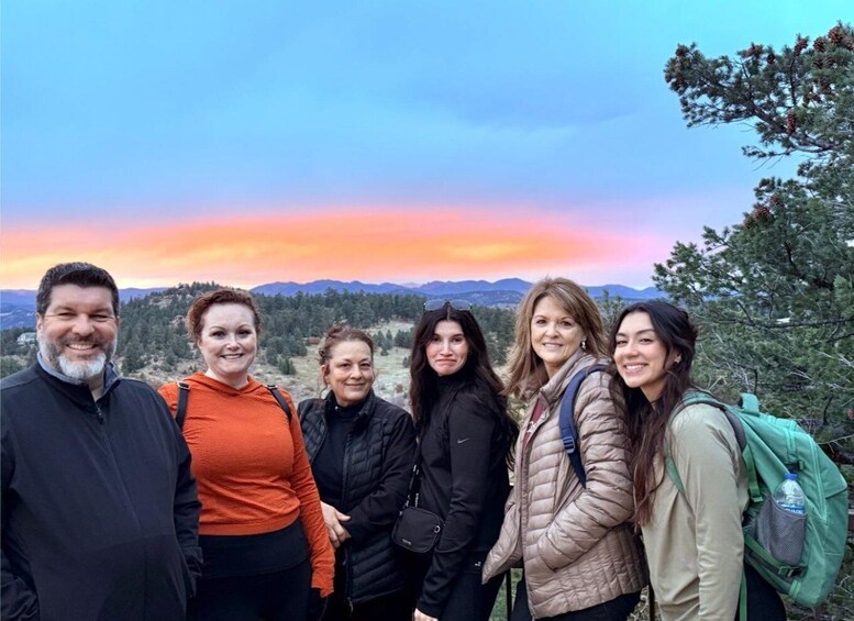 A group of people standing on a hill with a sunset in the background. 1