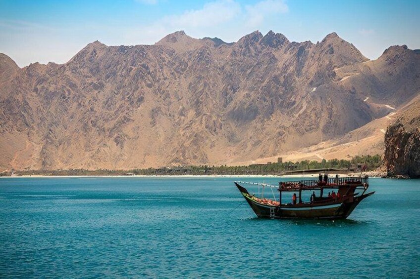 A boat on a calm body of water with mountains in the background. 2