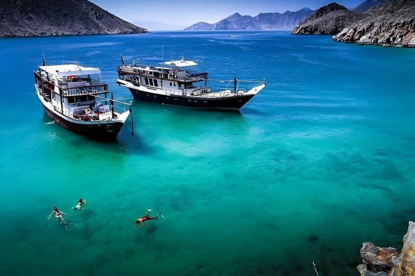 Two boats anchored in turquoise water with a mountainous landscape in the background. 5