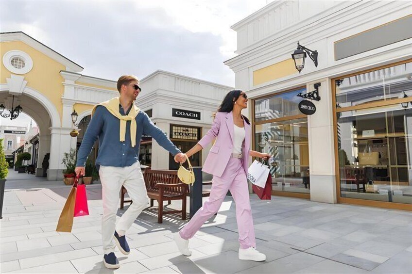 Two people walking on a shopping street, holding shopping bags. 5