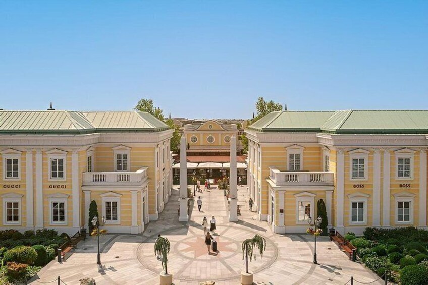 A grand building with multiple entrances, a central staircase, and a well-maintained courtyard with trees and benches. 1