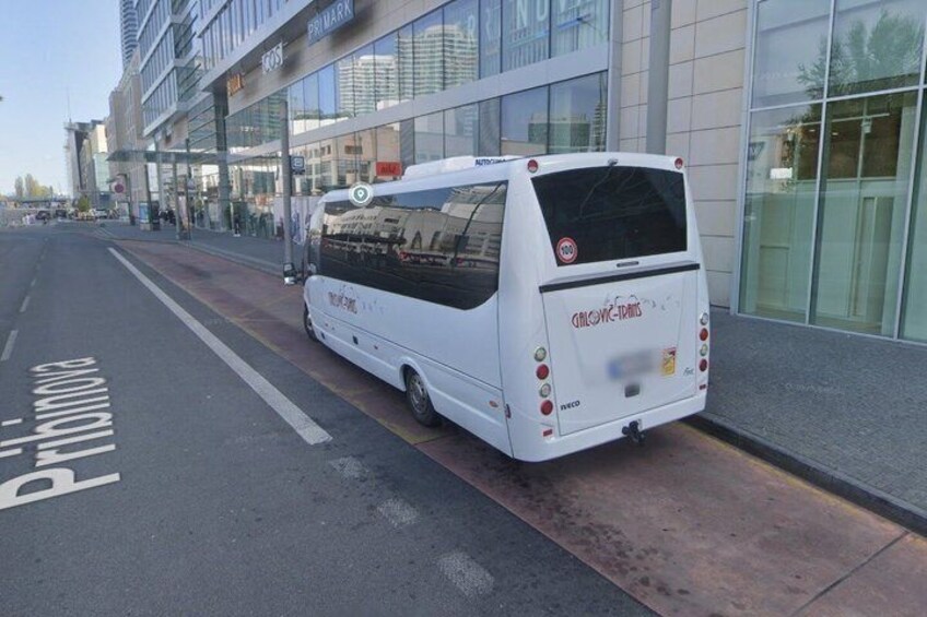 A white bus parked on the side of a road with a Primark store in the background. 2