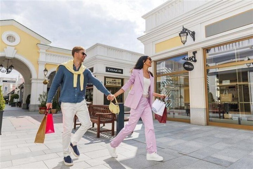 A couple walking on a shopping street with storefronts and an archway. 4