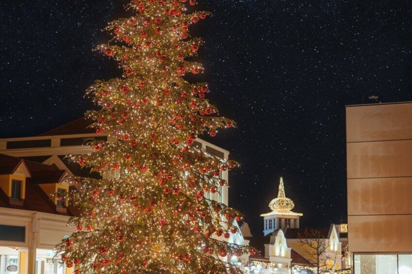 A large Christmas tree adorned with lights and ornaments, set against a night sky with visible stars. 3