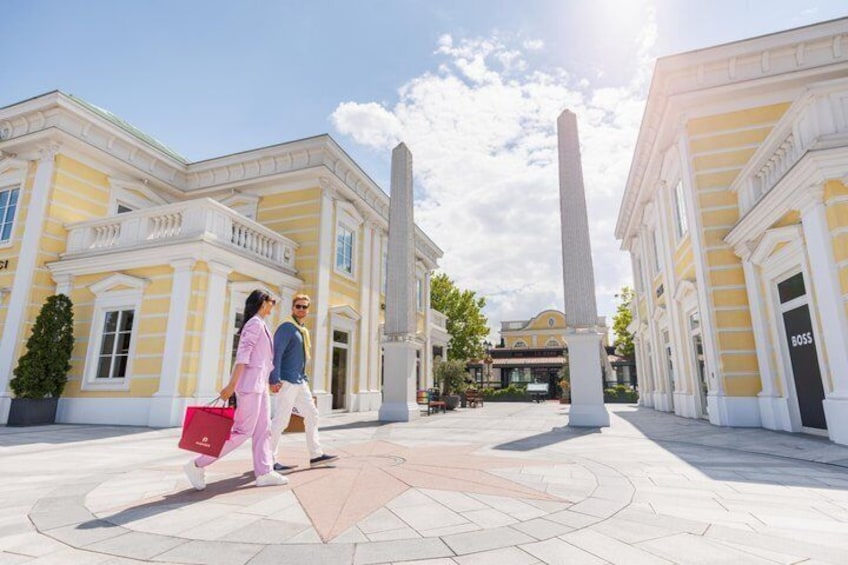 A historical building with yellow and white facades, a central obelisk, and a clear sky. 3