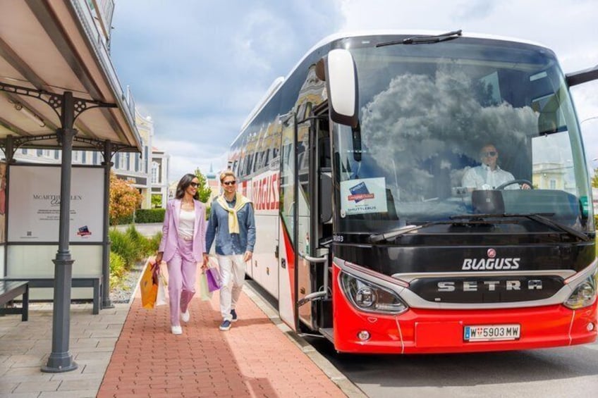 A red and black bus with the brand 'SETRA' and the model 'BIAGUSS' parked on a paved area with a building in the background. 2