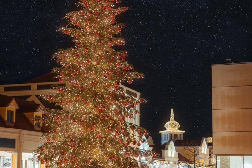 A large Christmas tree adorned with lights and ornaments, set against a night sky with visible stars. 3