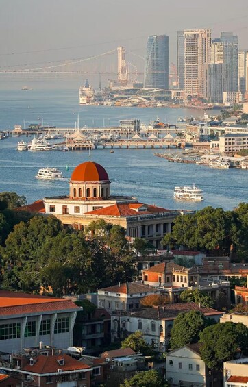 A coastal cityscape with a prominent domed building, a marina with boats, and modern high-rise buildings in the background. 2