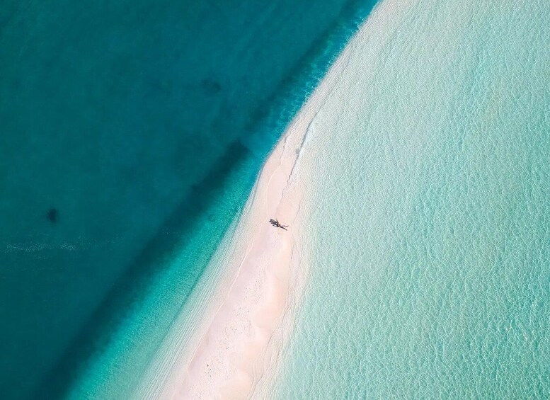 An aerial view of a beach with clear turquoise waters and a sandy shoreline. 2
