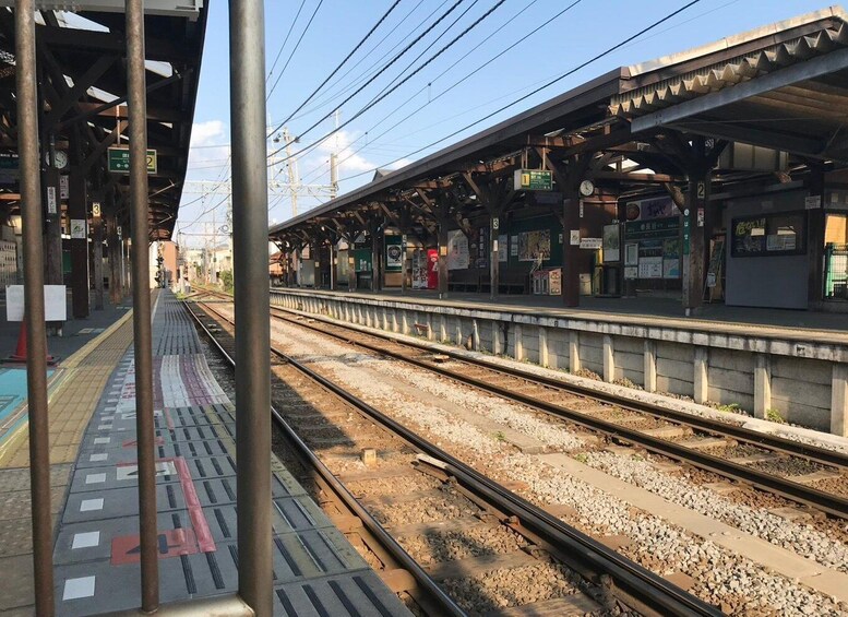 A railway station with multiple platforms, overhead wires, and a clock. 5