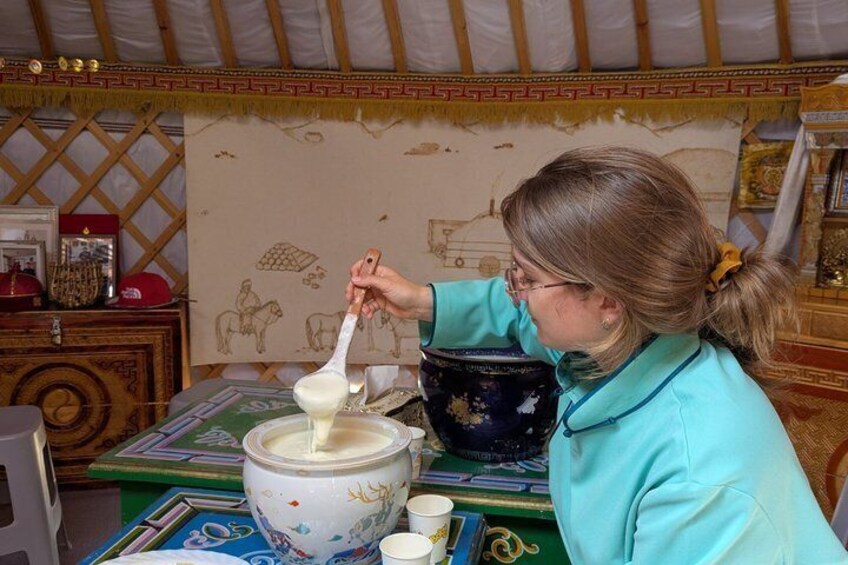 A person cooking in a traditional setting with a large pot and a ladle. 3