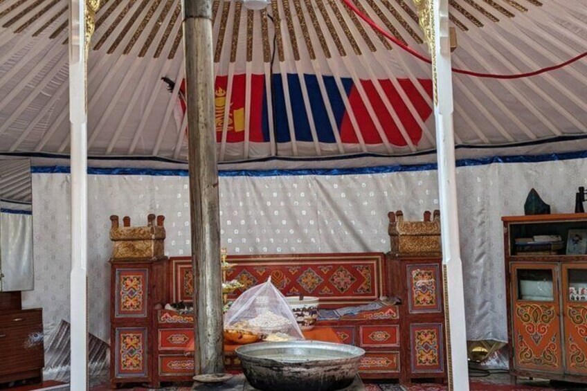 A tent with a striped canopy, a wooden bed with intricate designs, and a metal basin. 2