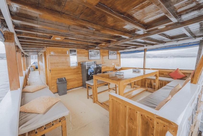 A wooden interior with a table, benches, and a view of the water outside. 2