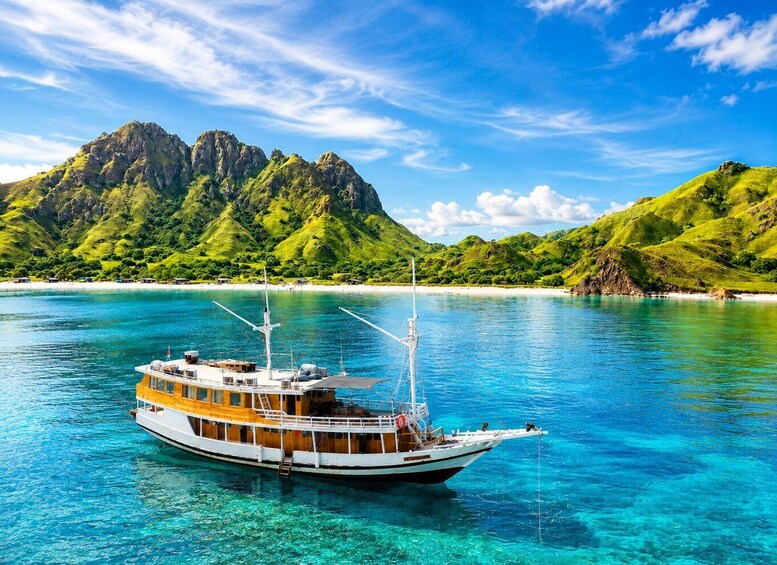 A boat on clear turquoise water with a mountainous landscape in the background. 1
