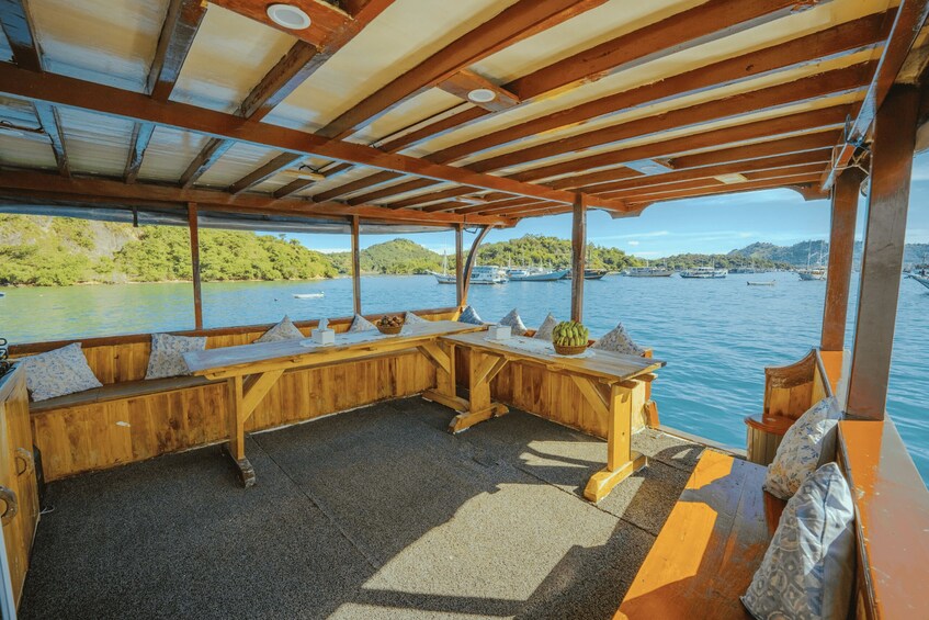 A covered wooden deck with a seating area overlooking a body of water with boats. 3
