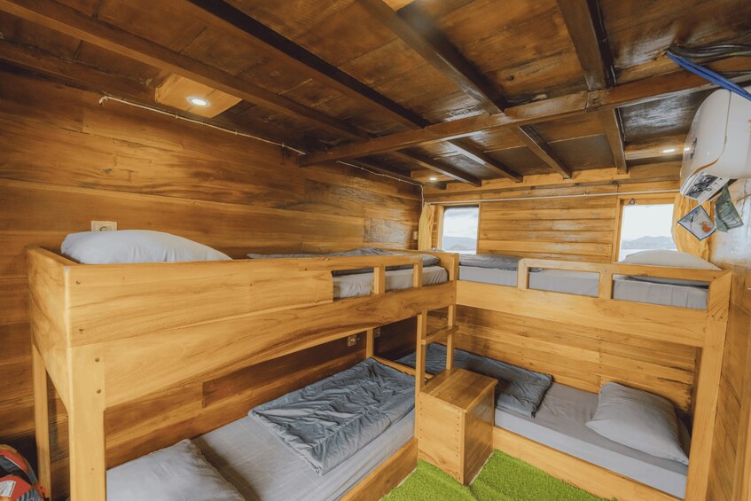 A cabin interior with wooden bunk beds, a small table, and a window. 4