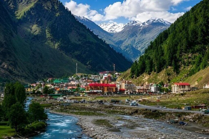 A town nestled in a valley with a river, surrounded by mountains and snow-capped peaks. 2