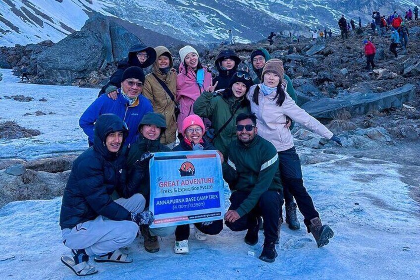 A group of people posing with a sign in a snowy mountainous area. 1