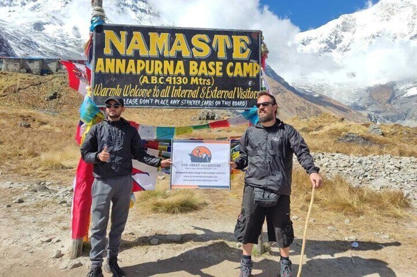 Two people standing in front of a sign for Namaste Annapura Base Camp. 2