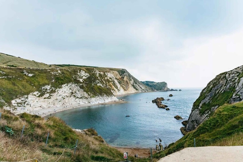 A coastal landscape with cliffs, a beach, and calm sea. 2
