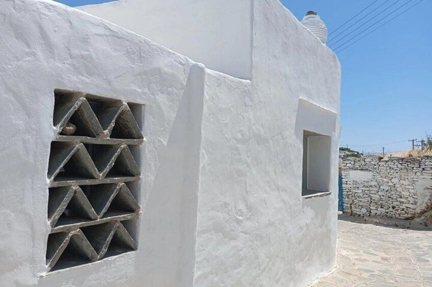 A white building with a unique window design and a stone wall in the background. 4