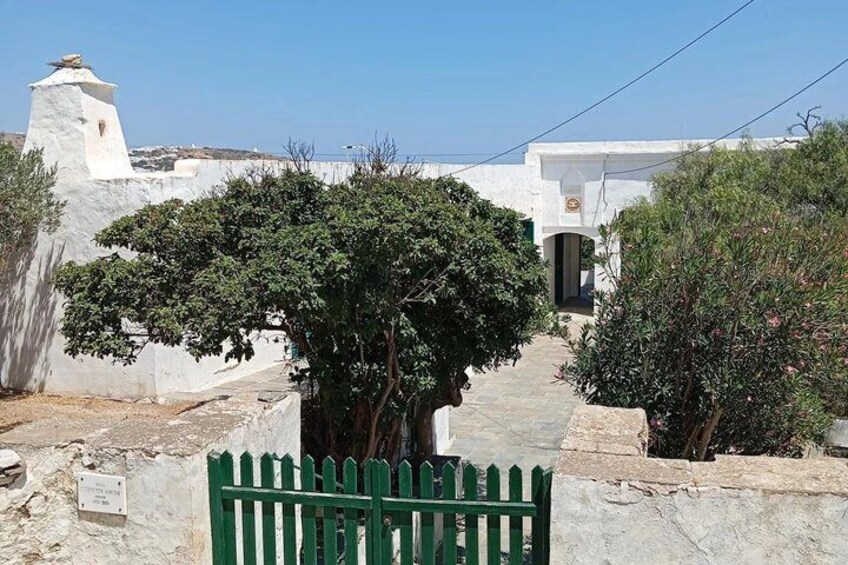 A white building with a tower, a green gate, and a pathway leading to a door. 5