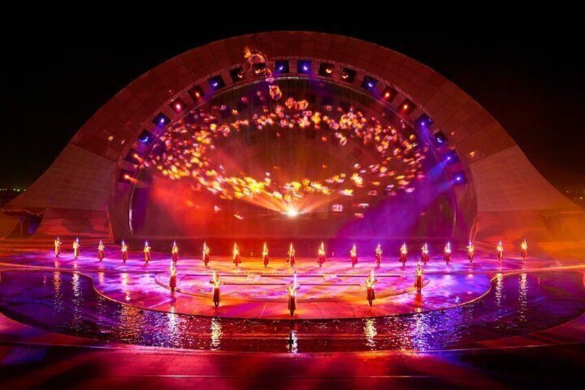 A large circular stage with a central light display and performers on the perimeter. 4
