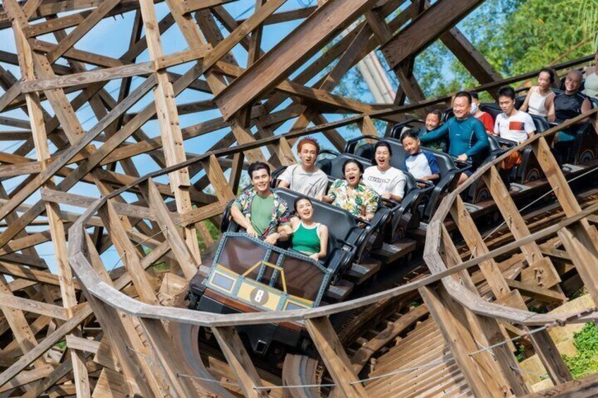 A wooden roller coaster with passengers. 1