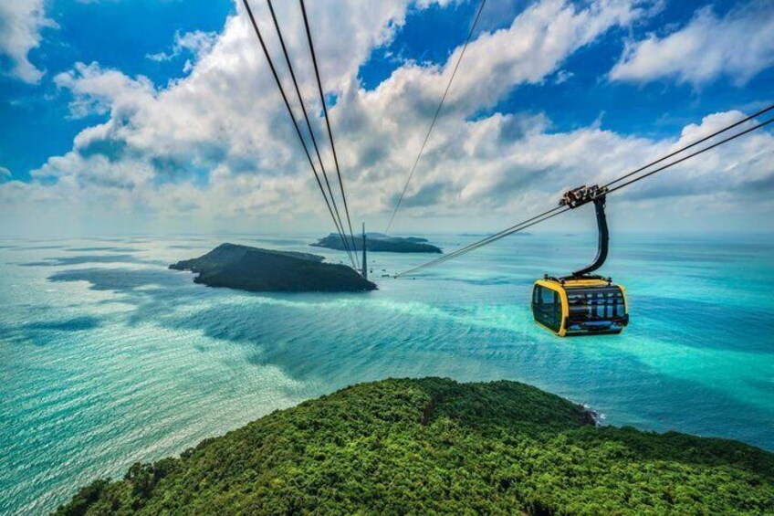 A cable car over turquoise waters, a small island, and lush greenery. 2