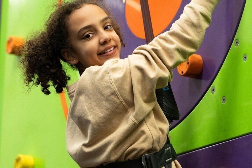 A child climbing a colorful indoor climbing wall. 4