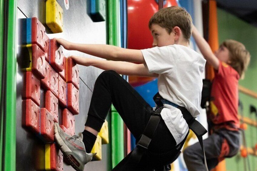 A child climbing a wall with colorful holds. 1