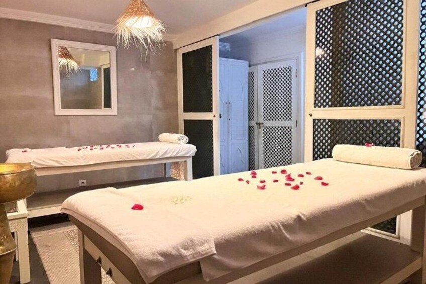 A spa room with a massage table, a small bathtub, and a mirror on the wall. 5