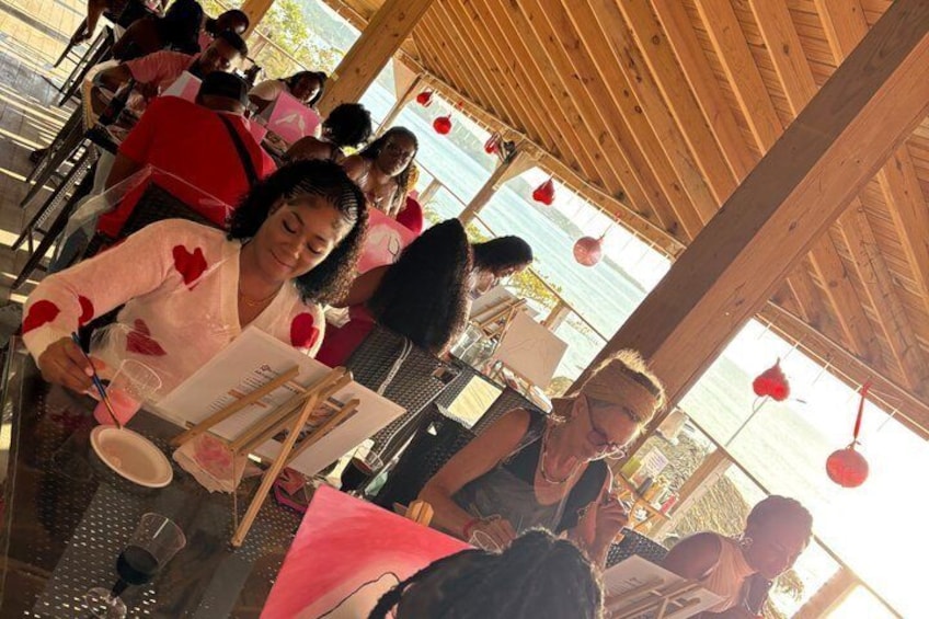 People sitting at tables under a wooden structure, possibly a gazebo, with a view of the outdoors. 3