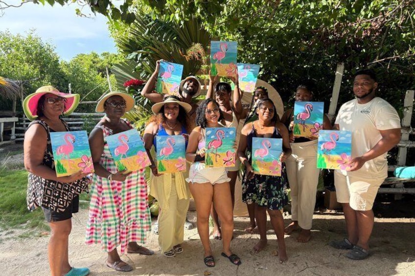A group of people holding painted canvases with a flamingo theme, standing outdoors under a tree. 1