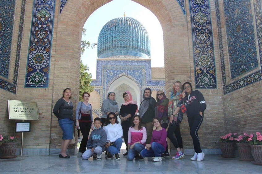 A group of people posing in front of a historic building with intricate tile work and a large dome. 3