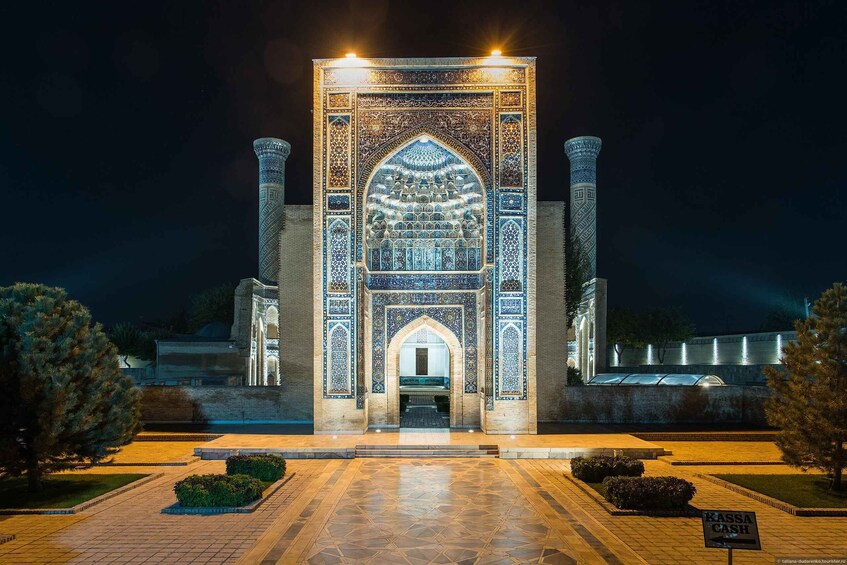 A night view of a historic building with intricate tile work and two tall columns. 1