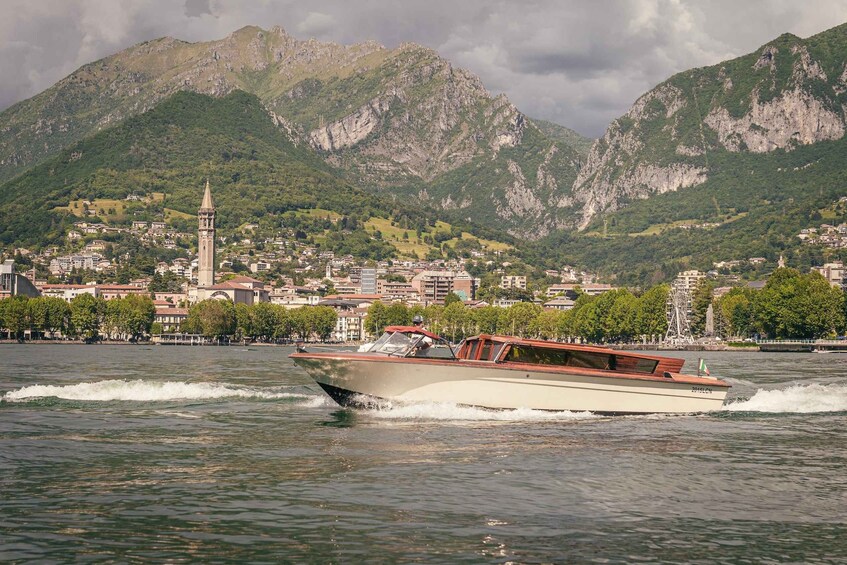 A boat speeding across a lake with a town and mountains in the background. 3
