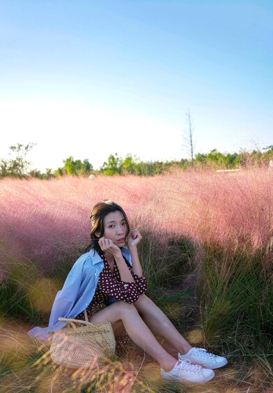 Eine Person sitzt in einem Feld mit hohem Gras und blauem Himmel. 4
