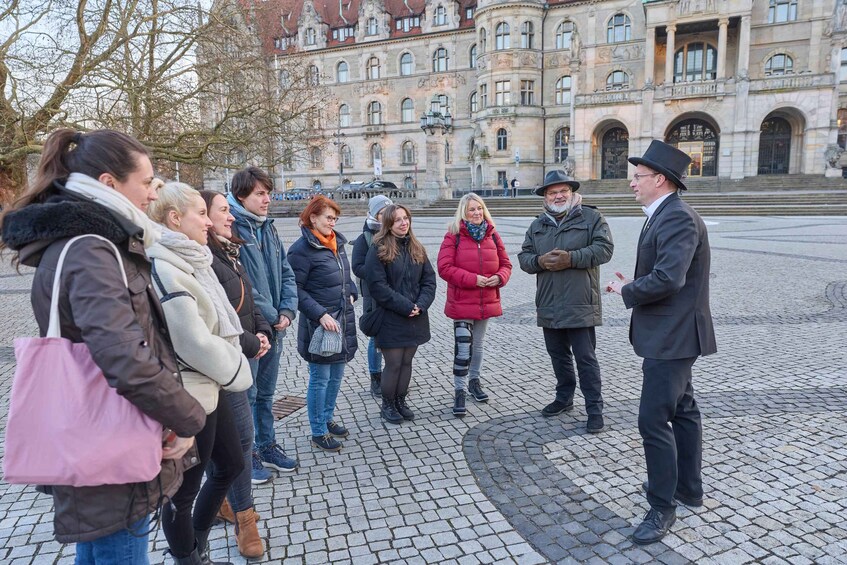 A group of people standing in a cobblestone square with a historic building in the background. 4