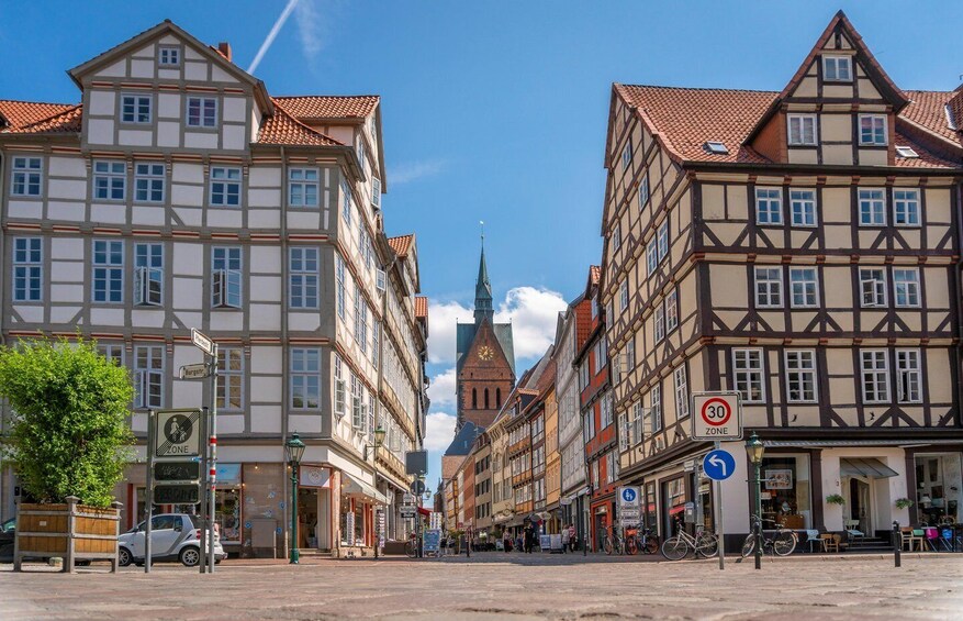 A street lined with traditional half-timbered buildings, a church spire, and a clear blue sky. 5