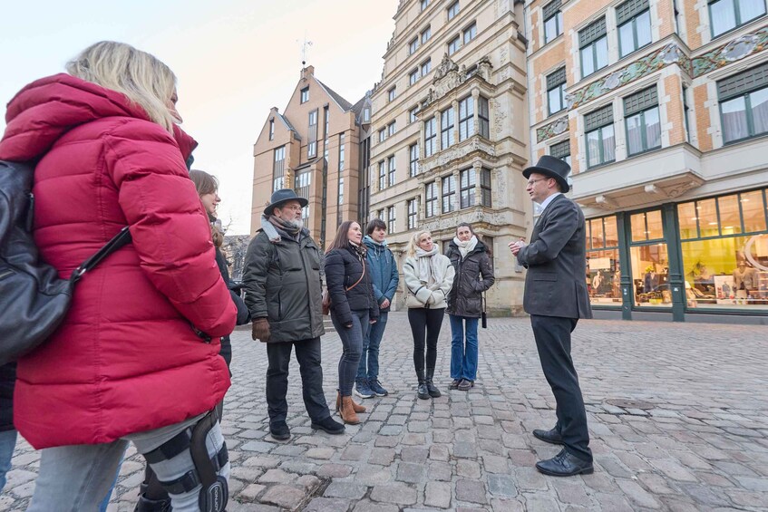 A group of people standing on a cobblestone street in front of a historic building with ornate architecture. 3