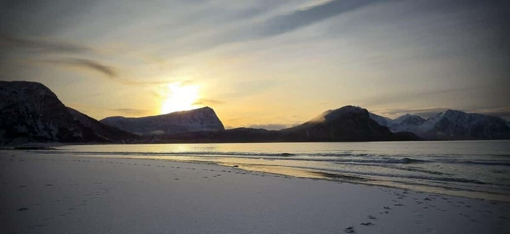 A beach with mountains in the background and the sun setting. 1