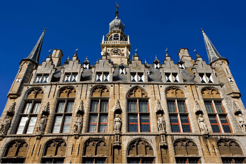 A historic building with ornate architecture, including a clock tower and statues. 1