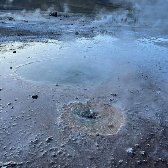 A geothermal area with steam vents and a circular hot spring. 5