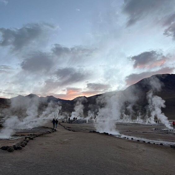 A geothermal area with steam vents and a sunset in the background. 4