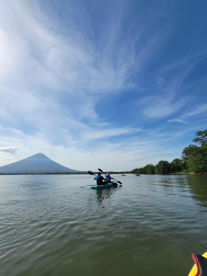 A calm lake with kayakers, a mountain in the background, and a clear sky. 3