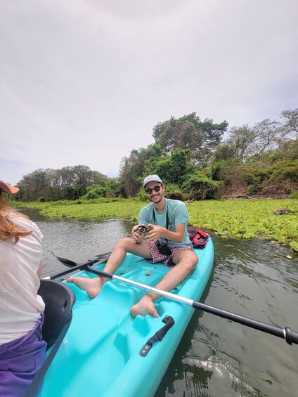 A person in a kayak on a river surrounded by greenery. 2