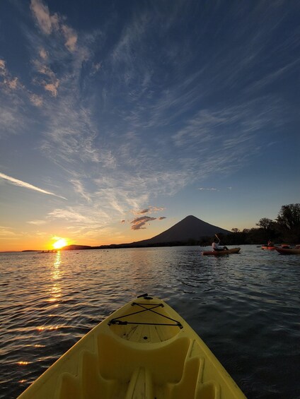 A sunset over a calm lake with kayaks and a mountain in the background. 5